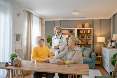 Olgun kadın doktor yaşlı çifti ziyaret ediyor karı koca konuşuyor ve teşhis ve tıbbi tedavi hakkında danışmanlık yapıyor gerçek insanlar sağlık hizmetleri kavramını kopyalıyor.