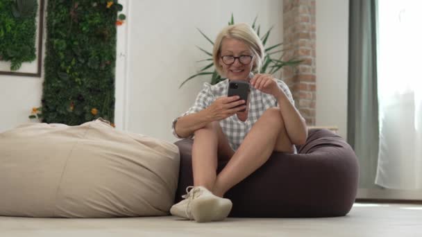一个成熟的高加索金发女人用手机用智能手机发短信 只有她一个人快乐 真实的人慢动作 — 图库视频影像