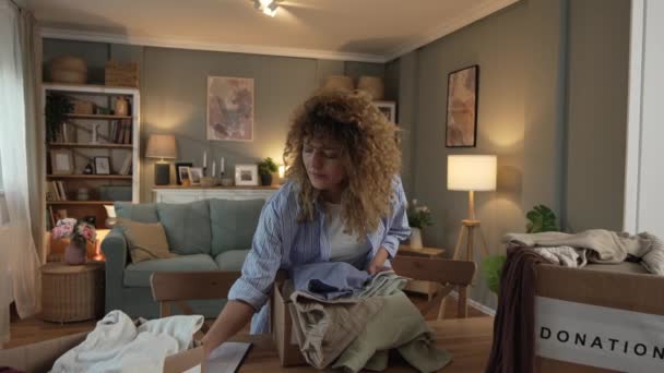 Kıvırcık Saçlı Beyaz Bir Kadın Giysilerini Hayır Işi Için Evde — Stok video