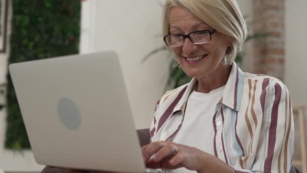 stock video One mature caucasian blonde woman work use laptop computer while sit at home