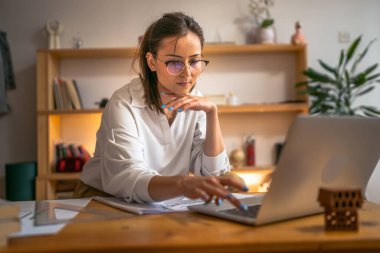 Genç beyaz kadın evde dizüstü bilgisayarın önünde ders çalışıyor - kadın kitap hazırlama sınavı ya da ödev sınavı çevrimiçi danışmanlık - eğitim ve öğrenim kavramı
