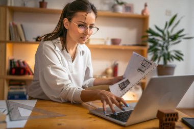 Genç beyaz kadın evde dizüstü bilgisayarın önünde ders çalışıyor - kadın kitap hazırlama sınavı ya da ödev sınavı çevrimiçi danışmanlık - eğitim ve öğrenim kavramı