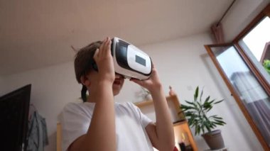 Erkek beyaz çocuk evde sanal gerçekliğin tadını çıkarıyor VR kulaklıklı UGC Kullanıcı tarafından oluşturulan amatör video içeriği 