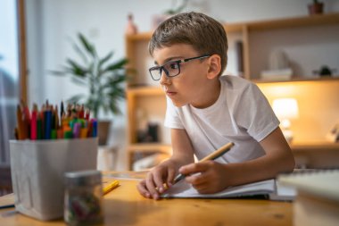 Genç çocuk öğrenci ödevlerini evde yapıyor.