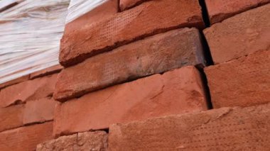 Depodaki palette bir yığın kırmızı kil tuğla var. Yaklaş.