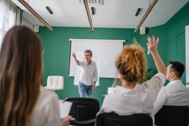 Koç eğitimi seminerdeki bir grup çalışana soruyu açıklar.