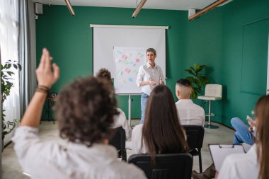 Koç eğitimi seminerdeki bir grup çalışana soruyu açıklar.