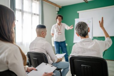 Koç eğitimi seminerdeki bir grup çalışana soruyu açıklar.