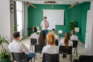 Koç eğitimi seminerdeki bir grup çalışana soruyu açıklar.