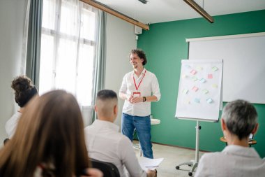 Koç eğitimi seminerdeki bir grup çalışana soruyu açıklar.