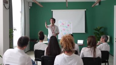 Koç eğitimi seminerdeki bir grup çalışana soruyu açıklar.