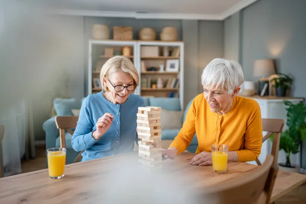 2人のシニア女性女性女性友人や家族姉妹遊びレジャーボードゲーム自宅で楽しいです年金受給者祖母あります一緒に時間を過ごす彼らの成熟した娘 — ストック写真