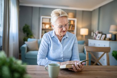 Yetişkin, yaşlı, Kafkasyalı, emekli, modern, kitap okuyan bir kadın gözlük takıyor.