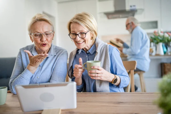 stock image two mature senior caucasian women family mother and daughter sisters or friends use digital tablet for video call at home real people copy space