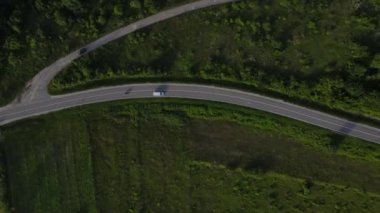 Sırbistan 'da yeşillik ve manzara taşımacılığı ve seyahat konseptiyle çevrili dolambaçlı yol boyunca giden yaz aracı otomobili sırasında bir dağ sırasındaki eğimli asfalt bir yolun hava aracı görüntüleri
