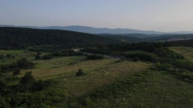 Sırbistan 'da yeşillik ve manzara taşımacılığı ve seyahat konseptiyle çevrili dolambaçlı yol boyunca giden yaz aracı otomobili sırasında bir dağ sırasındaki eğimli asfalt bir yolun hava aracı görüntüleri