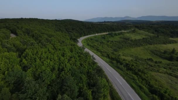 在塞尔维亚 夏季汽车沿着蜿蜒的道路行驶时 在山脉上一条弯曲的沥青路面的空中无人驾驶镜头 周围环绕着绿地 交通和旅行的概念 — 图库视频影像