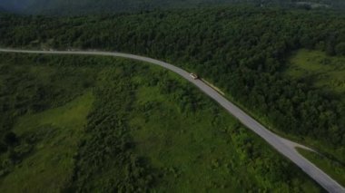 Sırbistan 'da yeşil ve manzara taşımacılığı ve seyahat konseptiyle çevrili dolambaçlı yol boyunca giden bahar aracı kamyonları sırasında bir dağ sırasındaki eğri asfalt bir yolun hava aracı görüntüleri