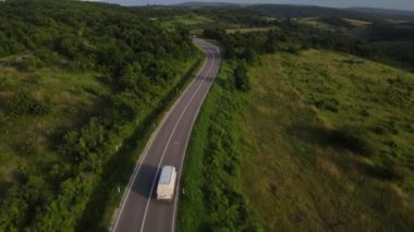 Sırbistan 'ın dolambaçlı yolu boyunca yeşil arazi taşıma ve seyahat konseptiyle çevrili bir şekilde giden yaz aracı minibüsü sırasında bir dağ sırasındaki eğri asfalt bir yolun hava aracı görüntüleri