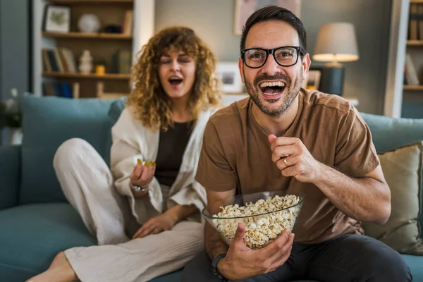 stock image Couple man and woman caucasian husband and wife or boyfriend and girlfriend sit on the sofa bed at home watch tv movie series with bowl of popcorn happy smile bonding love family concept copy space