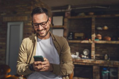 Beyaz tenli, sakallı ve gözlüklü bir adam güneşli bir günde açık havada oturur. Tişört giyer, cep telefonu kullanır. SMS mesajları atar, internete girer, internetten arama yapar.