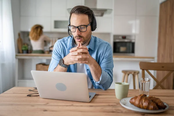 一名男子在家里工作 头上戴着耳机 头戴手提电脑 他的男性自由撰稿人支持认真考虑妻子的处境 — 图库照片