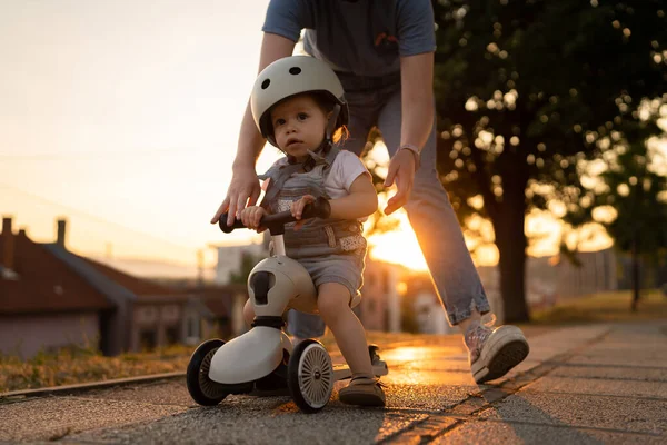 小さなCaucasian女の子幼児とともに母親遊び屋外で夏の夜に日没で3輪子供キックスクーター子供は保護ヘルメットを着用リアル人々コピースペースレジャー家族大人 — ストック写真