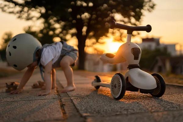 子供のキックスクーターの1人の女の子の小さな白人の幼児の秋は 夏の夜に屋外で遊んでいる間保護ヘルメットを身に着けています — ストック写真