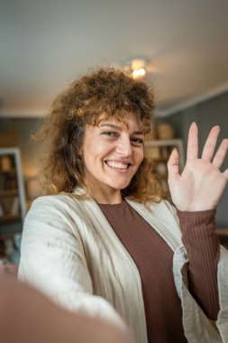 Beyaz bir kadın, kendinden emin, evde kıvırcık saçlı, mutlu, gülümseyen gerçek bir insan, uzay portresi, UGC Kullanıcı İçeriği