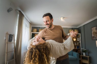 Mutlu yetişkin beyaz erkek ve kadın karı koca evde dans ediyor.