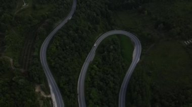 Sırbistan 'da yeşil ve manzara taşımacılığı ve seyahat konseptiyle çevrili dolambaçlı yol boyunca giden bahar aracı kamyonları sırasında bir dağ sırasındaki eğri asfalt bir yolun hava aracı görüntüleri
