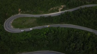Sırbistan 'da yeşil ve manzara taşımacılığı ve seyahat konseptiyle çevrili dolambaçlı yol boyunca giden bahar aracı kamyonları sırasında bir dağ sırasındaki eğri asfalt bir yolun hava aracı görüntüleri