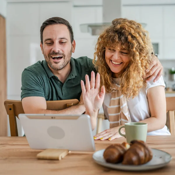 白人カップル男性と女性の夫と妻は自宅で楽しみながらオンラインで話しているビデオ通話を行うためにデジタルタブレットを使用しています家庭内生活のコンセプトコピースペースリアル人々 — ストック写真