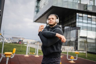 Şehirdeki açık spor salonunda antrenmandan önce ya da sonra esneyen bir adam. Gerçek insanlar sağlıklı yaşam tarzı konsepti. Amatör egzersiz.