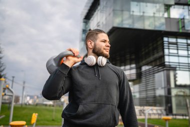 Kafkasyalı genç bir erkek sporcu gün içinde dışarıda Rus çanı Girya Kettlebell ağırlığında gerçek bir insan gibi poz veriyor.