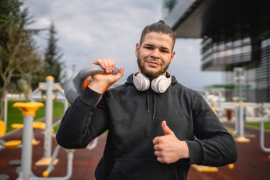 Kafkasyalı genç bir erkek sporcu gün içinde dışarıda Rus çanı Girya Kettlebell ağırlığında gerçek bir insan gibi poz veriyor.