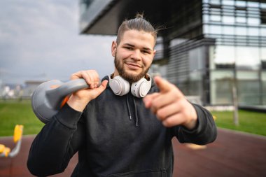 Kafkasyalı genç bir erkek sporcu gün içinde dışarıda Rus çanı Girya Kettlebell ağırlığında gerçek bir insan gibi poz veriyor.