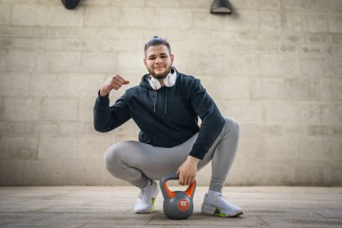 Kafkasyalı genç bir erkek sporcu gün içinde dışarıda Rus çanı Girya Kettlebell ağırlığında gerçek bir insan gibi poz veriyor.