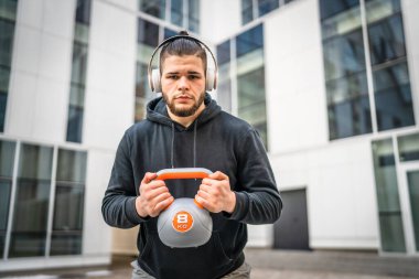 Kafkasyalı genç bir erkek sporcu gün içinde dışarıda Rus çanı Girya Kettlebell ağırlık egzersizi ile antrenman yapıyor.