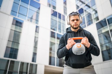 Kafkasyalı genç bir erkek sporcu gün içinde dışarıda Rus çanı Girya Kettlebell ağırlık egzersizi ile antrenman yapıyor.