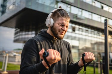 Yetişkin beyaz bir adam, günlük egzersiz rutininde lastik elastik direnç tüpleri kullanarak şehir dışında antrenman yapıyor. Gerçek insan sağlığı ve fitness konsepti kopyalama alanı kullanıyor.