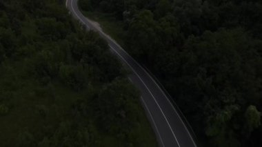 Sırbistan 'da yeşillik ve manzara taşımacılığı ve seyahatleriyle çevrili dolambaçlı yol boyunca giden yaz akşamı aracının bir dağ sırasındaki eğimli asfalt bir yolun hava aracı görüntüleri