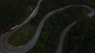 Sırbistan 'da yeşil ve manzara taşımacılığı ve seyahat konseptiyle çevrili dolambaçlı yol boyunca giden akşam aracı kamyonunda, dağ sırasındaki eğimli asfalt bir yolun hava aracı görüntüleri