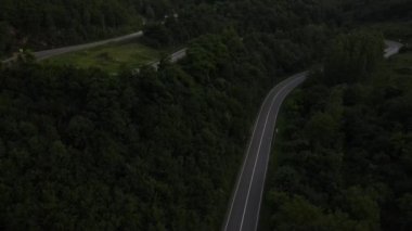 Sırbistan 'da yeşil ve manzara taşımacılığı ve seyahat konseptiyle çevrili dolambaçlı yol boyunca giden akşam aracı kamyonunda, dağ sırasındaki eğimli asfalt bir yolun hava aracı görüntüleri