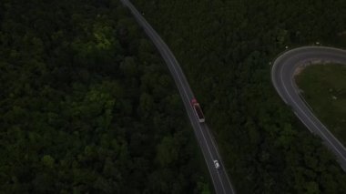 Sırbistan 'da yeşil ve manzara taşımacılığı ve seyahat konseptiyle çevrili dolambaçlı yol boyunca giden akşam aracı kamyonunda, dağ sırasındaki eğimli asfalt bir yolun hava aracı görüntüleri