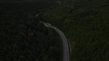 Sırbistan 'da yeşil ve manzara taşımacılığı ve seyahat konseptiyle çevrili dolambaçlı yol boyunca giden akşam aracı kamyonunda, dağ sırasındaki eğimli asfalt bir yolun hava aracı görüntüleri