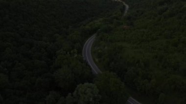 Sırbistan 'da yeşil ve manzara taşımacılığı ve seyahat konseptiyle çevrili dolambaçlı yol boyunca giden akşam aracı kamyonunda, dağ sırasındaki eğimli asfalt bir yolun hava aracı görüntüleri