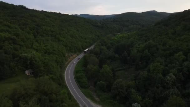 緑と風景輸送と旅行の概念に囲まれたセルビアの曲がりくねった道に沿って運転夜間車両トラック中の山岳地帯の曲技アスファルト道路の空中ドローン映像 — ストック動画