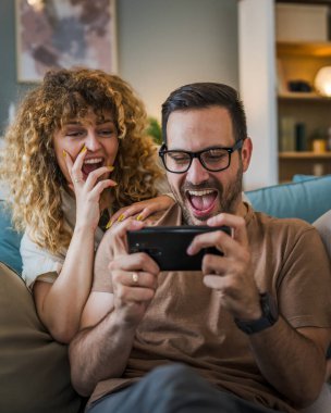 Yetişkin bir çift, beyaz bir karı koca, bir eş ya da bir sevgili video oyunu oynuyor cep telefonunda akıllı telefonlar, eğlence keyfi ve bağlanma konseptini kopyalayın.