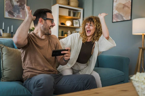 一对成年夫妇 男人和女人 高加索人的丈夫和妻子 男朋友和女朋友 他在家里玩电子游戏 拿着手机 智能手机 享受着乐趣 享受着结合的概念复制的空间 — 图库照片